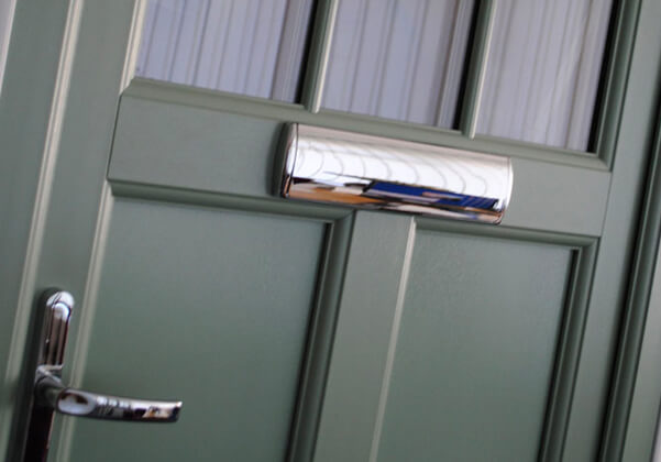 A gray residential front door showing a sliver handle and letterbox.